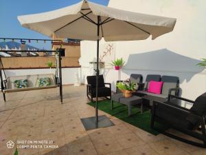 - un parasol sur une terrasse avec des chaises et des tables dans l'établissement Ático Sofía, gran terraza y barbacoa, à Fuengirola