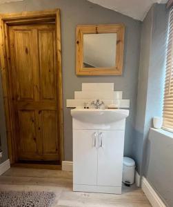 a bathroom with a sink and a mirror and a door at The Annexe in Winterbourne