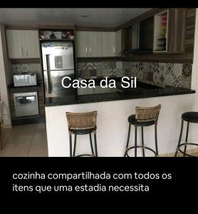 een keuken met 2 stoelen en een aanrecht met een koelkast bij Quarto Deluxe em Foz piscina wifi estacionamento cozinha E AR in Foz do Iguaçu