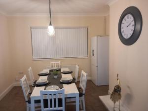 une salle à manger avec une table, des chaises et une horloge dans l'établissement Beautiful and Cosy 3 beds home for 6 guests near Doncaster Racecourse, 