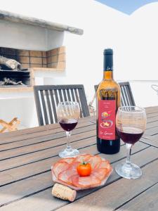 Casa Gercko 2 في يايثا: زجاجة من النبيذ وكأسين على طاولة خشبية