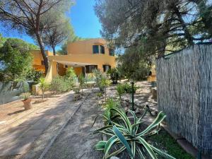 a house with a fence and plants in front of it at Villa Ginepro Sardegna Santa Margherita di Pula mare blu in Forte Village