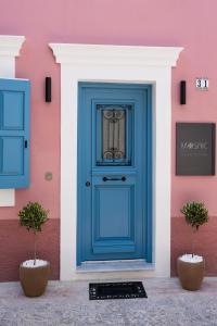 a blue door on a pink building with two plants at Mosaic Luxury Home in Rhodes Town