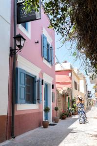 een vrouw die door een straat loopt voor een roze gebouw bij Mosaic Luxury Home in Rhodos-stad