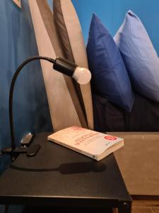una lámpara en una mesa con un libro. en Eco&Narciso apartment, en Monreale