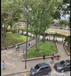 un groupe de personnes se promenant autour d'un parc avec des voitures dans l'établissement Hotel Milán, à Pereira