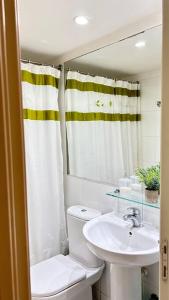 y baño con lavabo, aseo y cortina de ducha. en Departamento San Alfonso del Mar, primer piso, en Algarrobo