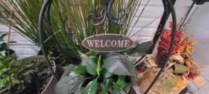 a sign that reads welcome in a bunch of plants at Kokomo INN Bed and Breakfast Ottawa-Gatineau's Only Tropical Riverfront B&B on the National Capital Cycling Pathway Route Verte #1 - for Adults Only - Chambre d'hôtes tropical aux berges des Outaouais BnB #17542O in Ottawa