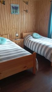 Duas camas num quarto com paredes de madeira em Cabaña los pajaritos de frutillar em Frutillar