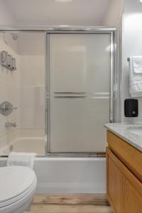 a bathroom with a shower and a toilet and a sink at Highliner Hotel- King Suite 312 with City View Hotel Room in Anchorage