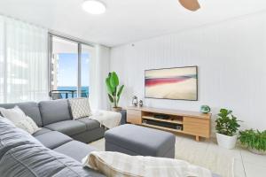 a living room with a couch and a tv at Stunning Esplanade Retreat with Ocean Views in Cairns +10 photos