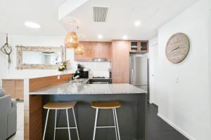a kitchen with a counter and two bar stools at Ocean Views at Mantra Trilogy in Cairns