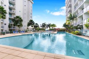 - une piscine dans un complexe avec des palmiers et des bâtiments dans l'établissement Ocean Views at Mantra Trilogy, à Cairns