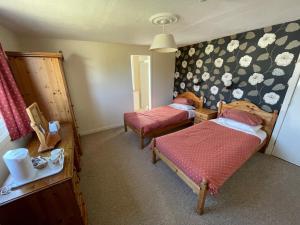 two beds in a room with flowers on the wall at Ben View Phoenix Hotel in Strontian