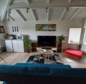 a living room with a blue couch and a tv at VILLA LAURAYM in Baie-Mahault