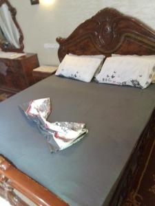 a bed with a wooden headboard and pillows on it at Immeuble chakir in Meknès