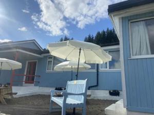a white chair with an umbrella in front of a house at Ben View Phoenix Hotel in Strontian