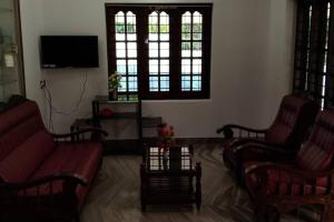 - un salon avec deux chaises et une télévision dans l'établissement Holiday homes in kidangoor kottayam kerala, à Kottayam