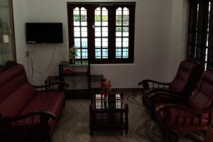 コッタヤムにあるHoliday homes in kidangoor kottayam keralaの椅子2脚とテレビのあるリビングルーム