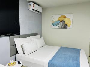 Un dormitorio con una cama blanca y una pintura en Edifício Creta, en São Luís