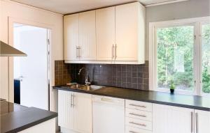 uma cozinha com armários brancos e um lavatório em 3 Bedroom Nice Home In Lammhult em Lammhult