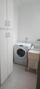a white laundry room with a washing machine and a sink at Casa das Camelias in Vigo