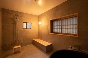 uma casa de banho com uma banheira e um chuveiro com uma janela em Villa Kasashima en. 