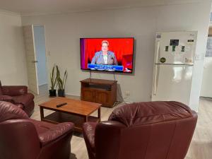 uma sala de estar com 2 sofás e uma televisão de ecrã plano em Single room share bathroom and kitchen em Perth