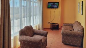 a living room with two chairs and a television at Cabañas Las Flores - Barrio residencial La Herradura in Coquimbo