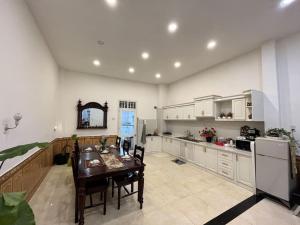 cocina con mesa de comedor y cocina con armarios blancos en VINTAGE HOUSE (Full house) en Xuan An