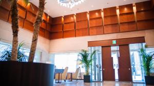 a lobby with tables and chairs and palm trees at Mitsui Garden Hotel Kumamoto in Kumamoto