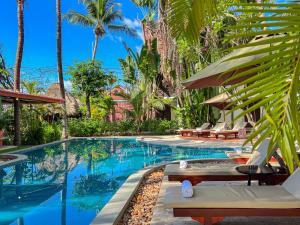 a pool at a resort with chairs and palm trees at Natural Relax Villa in Siem Reap