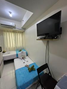 a room with two beds and a flat screen tv at Staycation Studio at Green Residences in Manila