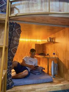 - un garçon assis sur un matelas dans un lit superposé dans l'établissement Sky Homestay Ha Giang, à Ha Giang