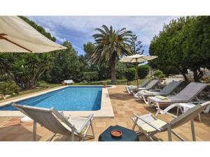 a row of chairs and a swimming pool with umbrellas at Belvilla by OYO T rtolas in Alaior