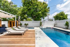 a pool with chaise lounge chairs next to a wooden deck at New luxury entertaining house with Pool Spa Sauna Tesla charger Pets in Los Angeles