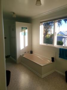 un ampio bagno con vasca e due finestre di Pohutukawa Villa 