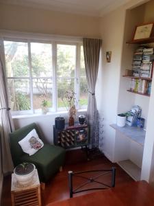 uma sala de estar com uma cadeira verde e uma janela em Pohutukawa Villa 