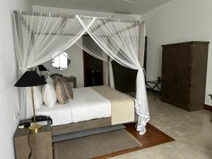 a bedroom with a canopy bed with white curtains at The Villa by Contemporary Ceylon in Wadduwa