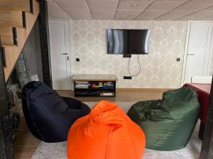 sala de estar con 2 pufs y TV de pantalla plana en Современные и уютные аппартаменты, en Burabay
