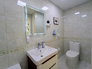 La salle de bains est pourvue d'un lavabo, de toilettes et d'un miroir. dans l'établissement Tsengeldekh:Cozy 1 BR Apt•Queen bed•Naadam stadium, à Oulan-Bator