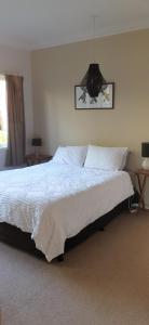 1 dormitorio con 1 cama blanca grande con lámpara de araña en Pohutukawa Villa 