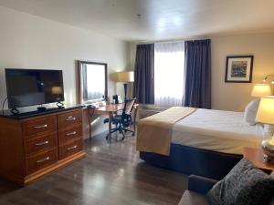 a hotel room with a bed and a desk and a television at Toppenish Inn and Suites in Toppenish