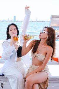 two women sitting on a boat drinking beer at Golden Rose Hotel by THG in Danang