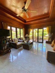 a living room with couches and a ceiling fan at Baan Laem Noi Villa's in Mae Nam