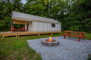 a tent with a fire pit and a picnic table at Roaring River Luxury Glamping #4 in Cassville