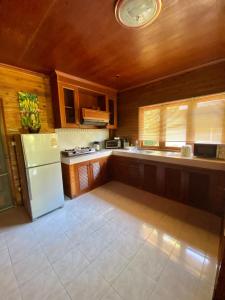 a kitchen with a white refrigerator and wooden cabinets at Baan Laem Noi Villa's in Mae Nam