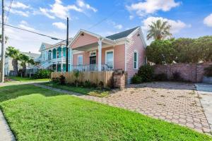 a pink house with a fence in a yard at The Anchor Beach House in Galveston