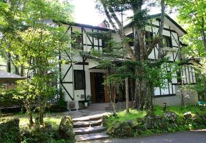 una gran casa blanca con árboles delante de ella en Pension Marie - Vacation STAY 29997v, en Yamanakako