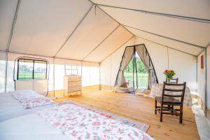 a bedroom in a tent with a bed and a chair at Roaring River Luxury Glamping #5 in Cassville